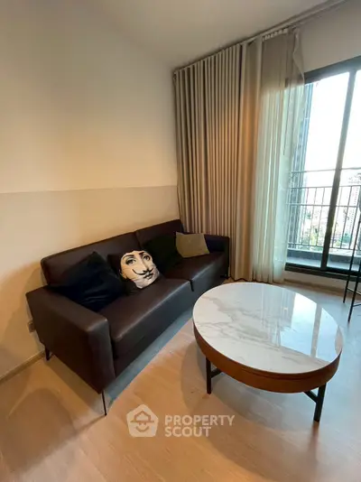 Modern living room with stylish sofa and round marble coffee table near large window.