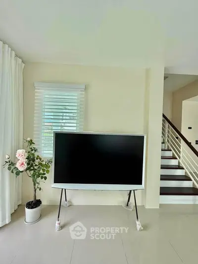 Modern living room with sleek TV and elegant staircase, perfect for stylish home entertainment.