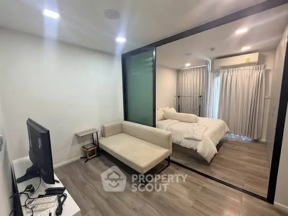 Modern studio apartment with sleek design and cozy bedroom separated by glass partition.