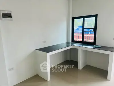 Modern minimalist study corner with sleek black countertop and large window view.