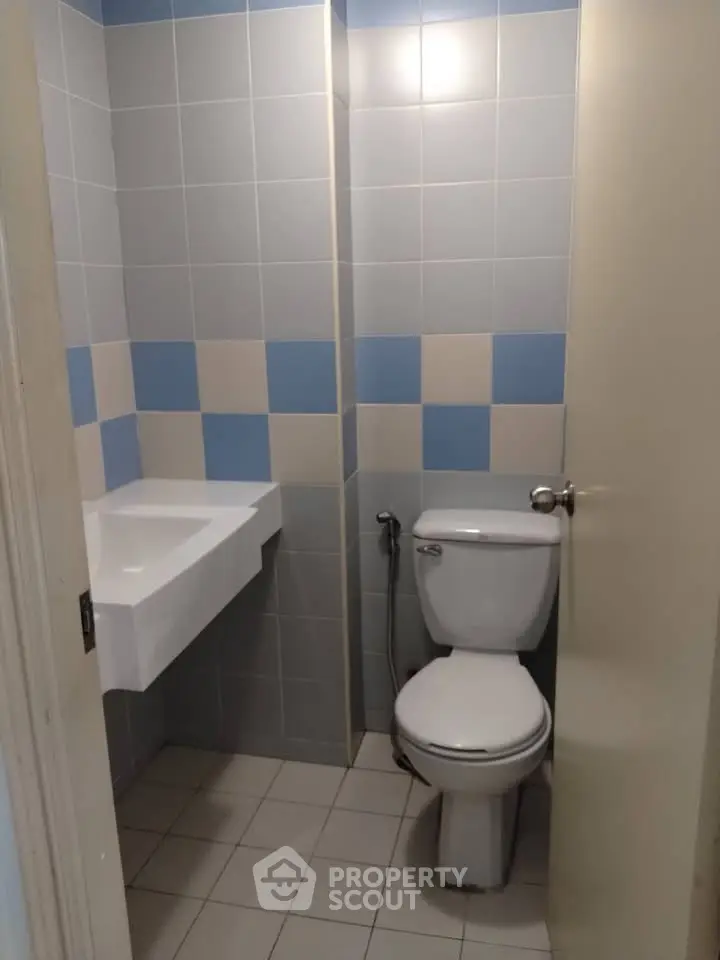 Compact bathroom with modern fixtures and tiled walls in a real estate property.