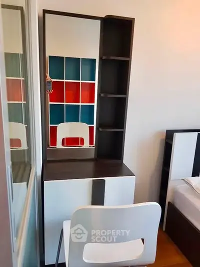 Modern bedroom with stylish vanity and colorful shelving, perfect for urban living.