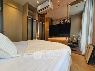 Modern bedroom with cozy decor and large TV, featuring mirrored wardrobe and air conditioning.