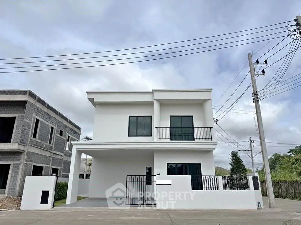 Modern two-story white house with balcony and gated driveway in suburban neighborhood.