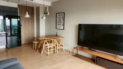 Modern living room with sleek furniture and large TV, open layout with dining area, and stylish decor.