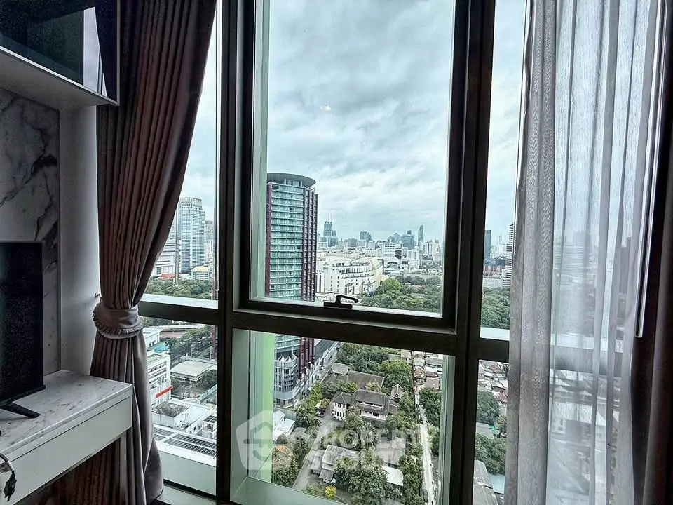 Stunning cityscape view from high-rise apartment window with elegant curtains.