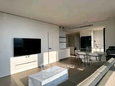 Modern living room with sleek furniture and large TV, featuring open layout and natural light.