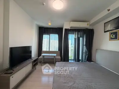 Modern bedroom with balcony view, featuring sleek furniture and ample natural light.