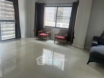 Spacious living room with large windows and modern furniture in a bright apartment.