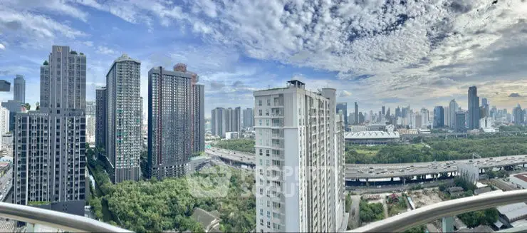 Stunning cityscape view from high-rise balcony with lush greenery and skyline.