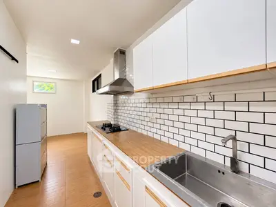 Modern kitchen with sleek white cabinets, wooden countertops, and subway tile backsplash.