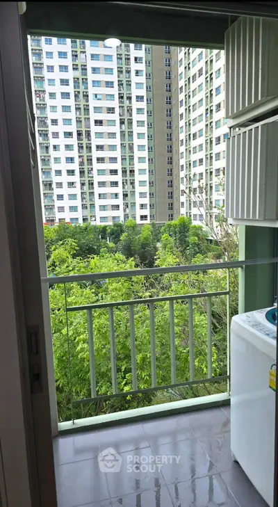 Modern apartment balcony with lush green view and washing machine