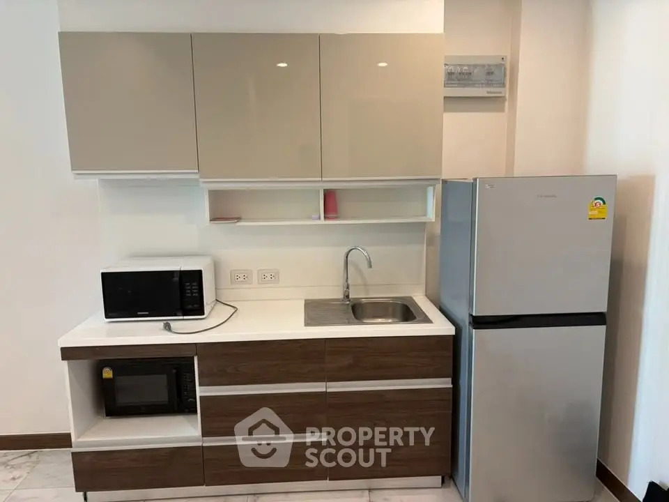 Modern kitchen with sleek cabinets, microwave, and fridge in a compact layout.