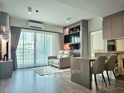 Modern living room with sleek furniture and large window offering natural light.