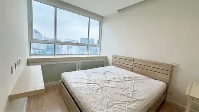 Bright bedroom with large window offering city views and modern furnishings.