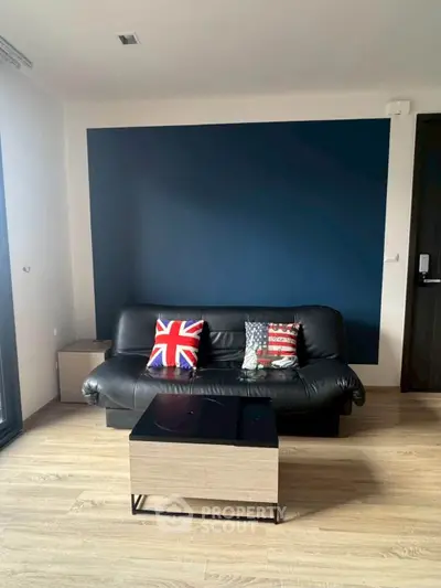 Modern living room with stylish black sofa and decorative pillows, featuring a sleek coffee table on wooden flooring.