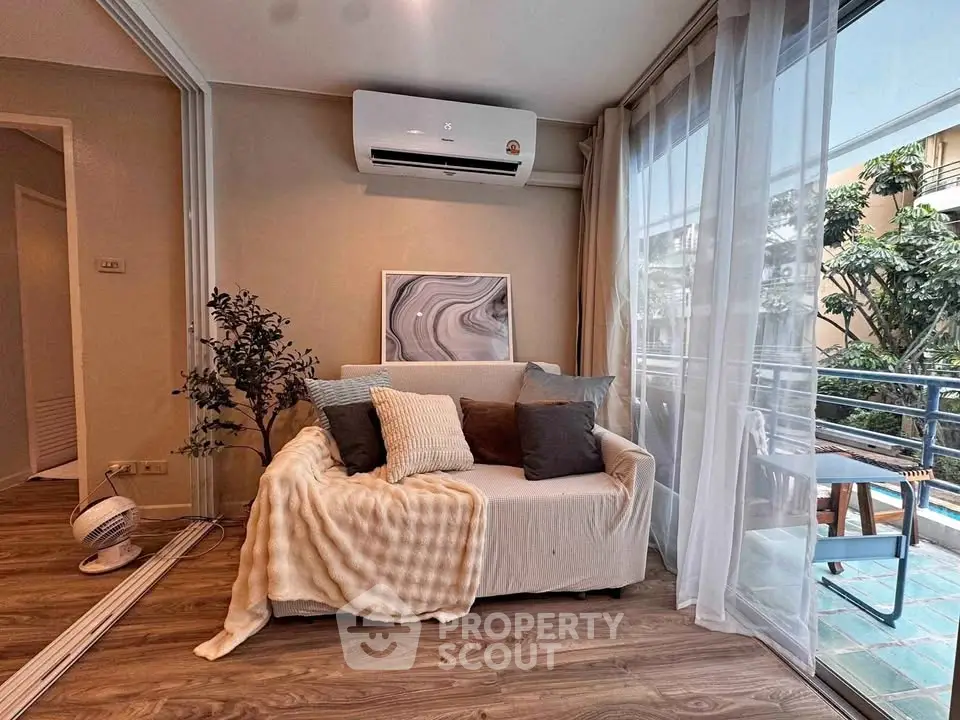 Cozy living room with air conditioning and balcony access, featuring stylish decor and natural light.