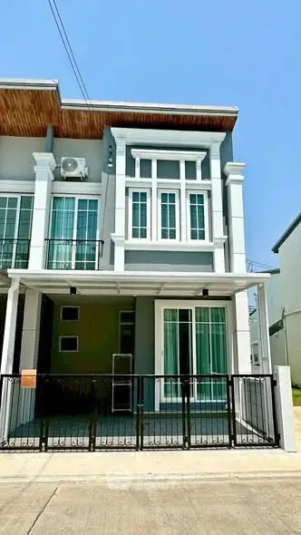 Modern townhouse exterior with stylish facade and gated entrance in a sunny neighborhood.