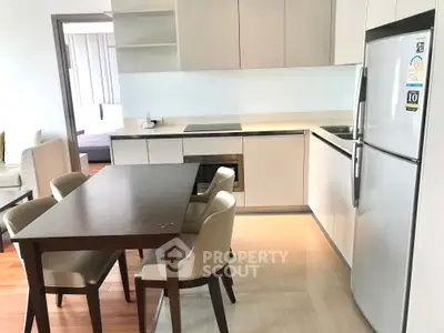 Modern kitchen with sleek cabinetry and dining area in open layout apartment.
