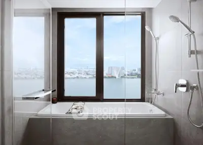 Luxurious bathroom with stunning city and river view from large window.