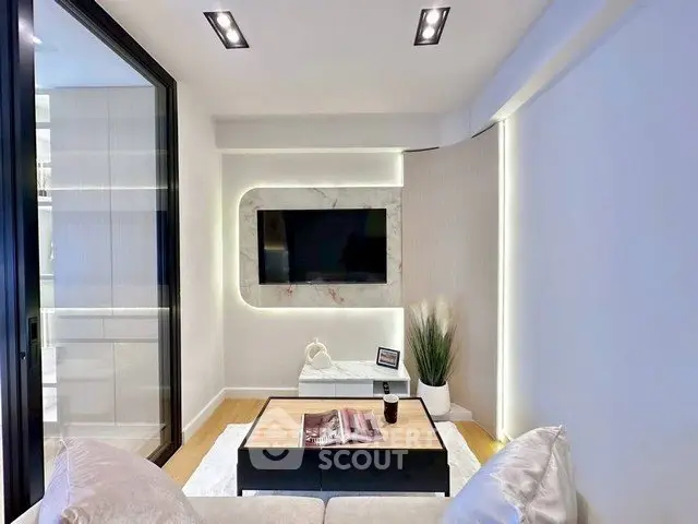 Modern living room with sleek design, featuring a wall-mounted TV and stylish lighting.
