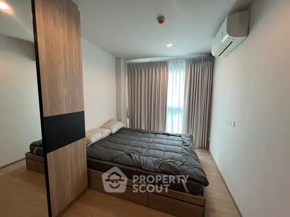 Modern bedroom with sleek design, featuring a cozy bed and ample natural light through large window.