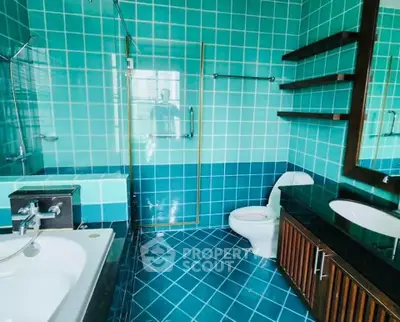 Luxurious bathroom with turquoise tiles, glass shower, and modern fixtures for a spa-like experience.