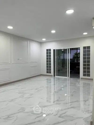 Spacious modern living room with marble flooring and sliding glass doors.