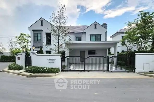 Elegant modern house with gated entrance and lush greenery in a serene neighborhood.