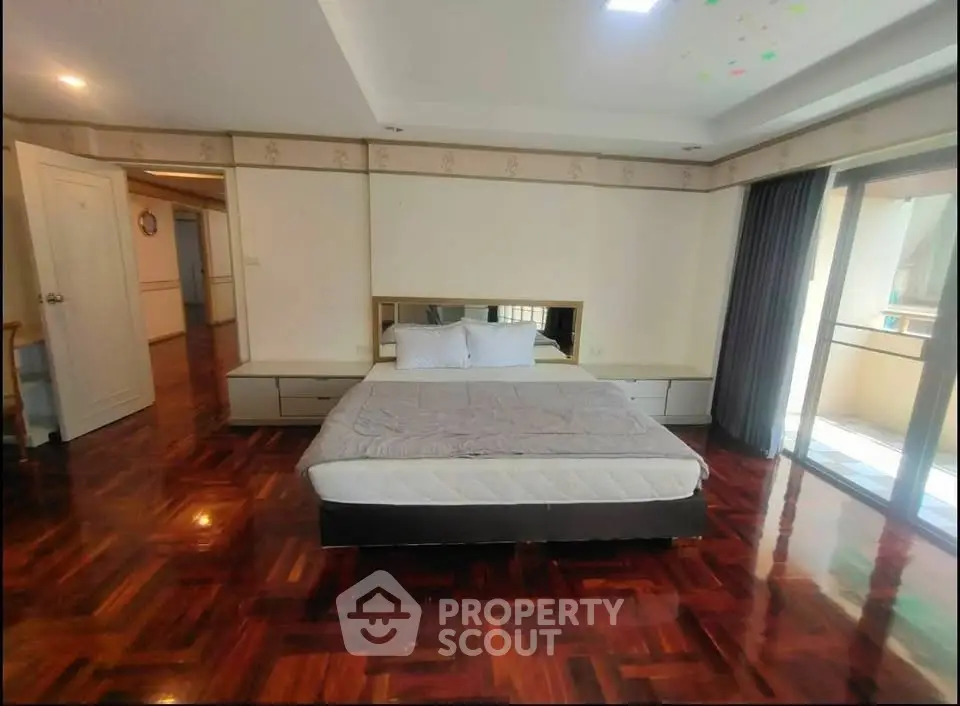 Spacious bedroom with elegant wooden flooring and balcony access