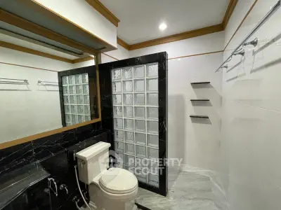Modern bathroom with glass block partition and sleek black accents