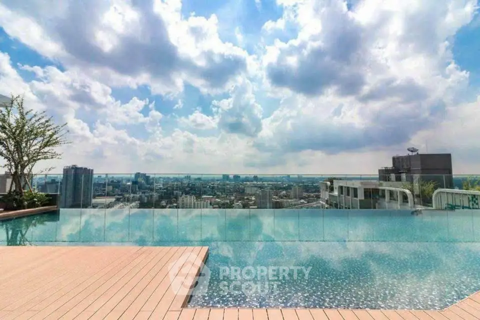 Stunning rooftop infinity pool with panoramic city skyline view under a vibrant sky.