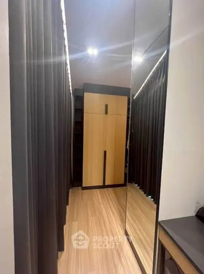 Modern walk-in closet with sleek wooden flooring and mirrored doors.