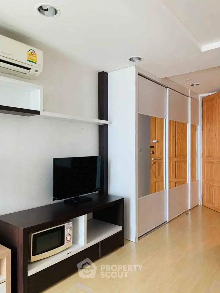Modern living room with sleek TV stand, microwave, and air conditioning in a stylish apartment.