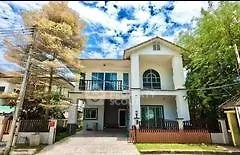Charming two-story house with lush greenery and spacious driveway
