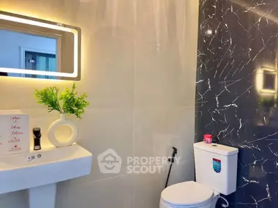 Modern bathroom with sleek design, illuminated mirror, and elegant black marble accent wall.