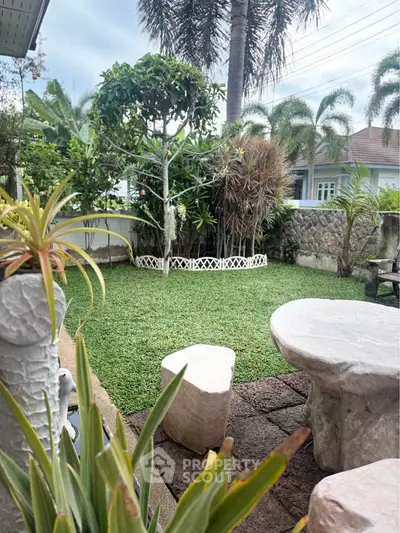 Charming garden oasis with lush greenery and stone seating, perfect for relaxation and outdoor enjoyment.