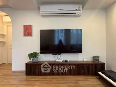 Modern living room with wall-mounted TV, air conditioning, and stylish wooden cabinet.