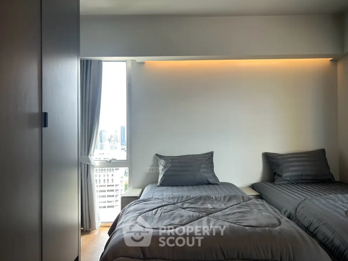 Modern bedroom with twin beds and city view, featuring sleek design and ambient lighting.