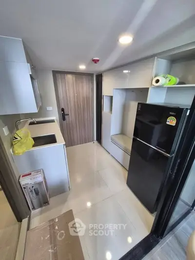 Modern compact kitchen with sleek cabinetry and black refrigerator in a stylish apartment.