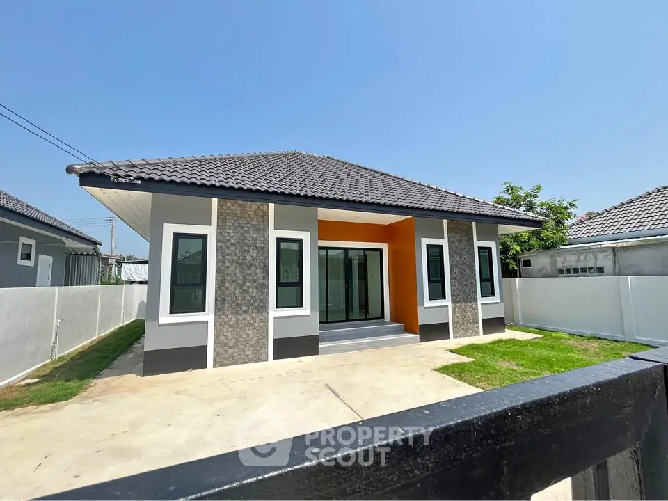 Charming single-story house with modern design and spacious yard under clear blue sky.
