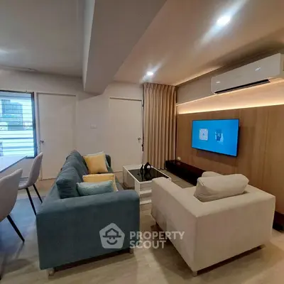 Modern living room with stylish furniture and wall-mounted TV, featuring cozy seating and ambient lighting.