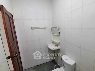 Compact bathroom with white tiles and basic fixtures in a real estate property.