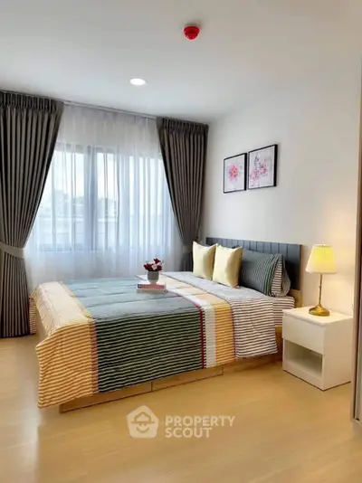 Modern bedroom with stylish decor, large window, and cozy bedding in a bright apartment.