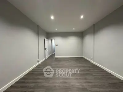 Spacious empty room with modern flooring and recessed lighting, perfect for customization.