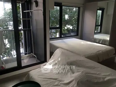 Spacious bedroom with large windows and balcony access, offering a serene view of lush greenery.