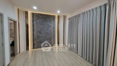 Spacious modern living room with elegant marble accent wall and floor-to-ceiling curtains.
