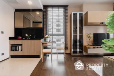 Chic modern apartment with an open layout kitchen featuring sleek black countertops, adjacent to a cozy dining area with natural light filtering through wooden blinds.