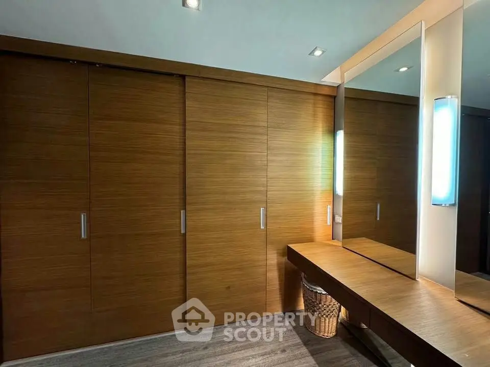 Spacious modern dressing area with wooden sliding doors and large mirror.