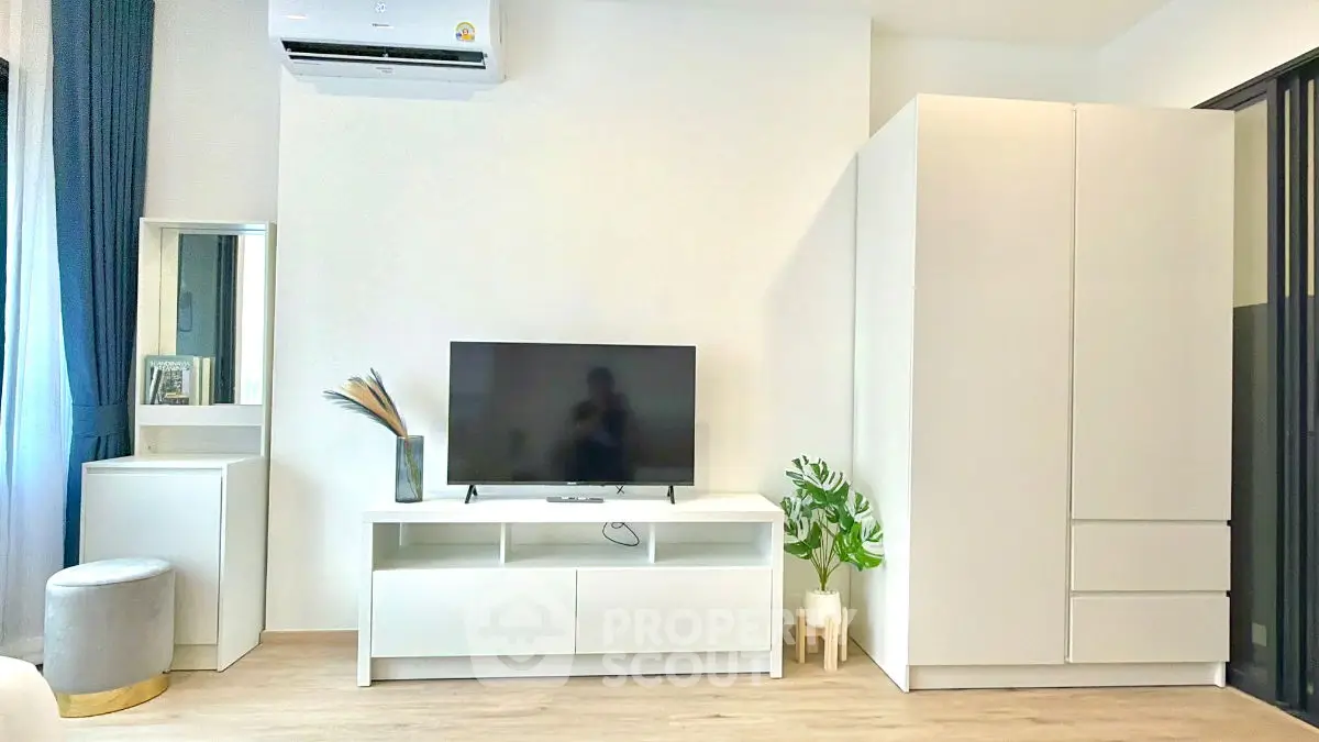 Modern living room with sleek white furniture and TV, perfect for minimalist style enthusiasts.
